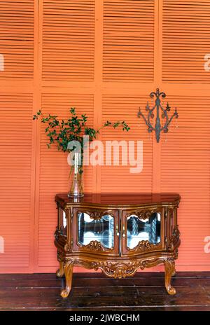Décoration intérieure élégante dans le salon avec commode rétro en bois. Murs orange ou terre cuite. Décoration d'intérieur. Photo de haute qualité Banque D'Images