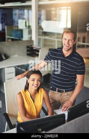Ils doivent leur succès au travail d'équipe. Portrait de deux collègues souriants travaillant ensemble dans un bureau. Banque D'Images