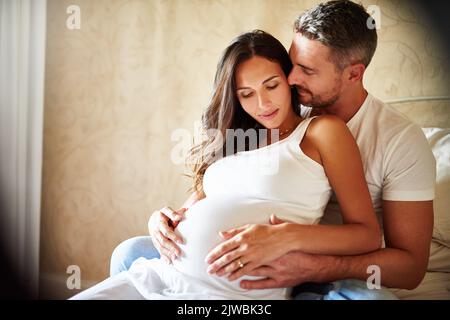 De beaux débuts. Un mari et une femme enceinte assis ensemble dans une chambre. Banque D'Images
