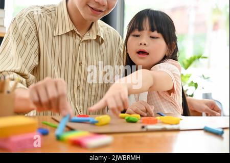 Bonne joyeuse jeune fille asiatique ayant un grand moment avec son père, faisant une activité amusante et aime mouler la pâte avec son père. Banque D'Images