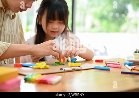 Happy Asian papa et fille aime mouler de l'argile colorée ou jouer la pâte ensemble à la maison. Mise au point sélective sur les objets. Image rognée Banque D'Images