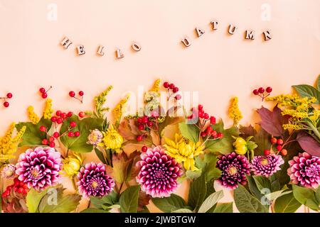 composition automnale festive de fleurs coupées, feuilles et baies de jardin. fond beige avec inscription -hello automnal. bordure florale Banque D'Images