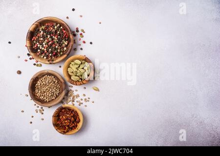 Vue de dessus de mélanger des épices vives ou des assaisonnements dans de petits bols en bois comme ingrédient pour des aliments sains sur fond de béton gris Banque D'Images