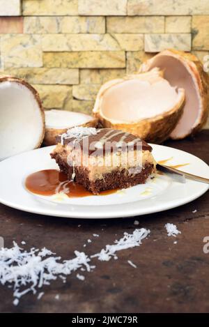 Gâteau de bounty sur plaque blanche avec une cuillère et une sauce caramel Banque D'Images