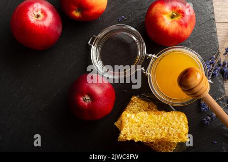 Pot Mason avec un balancier au miel et des pommes rouges et un nid d'abeille sur la table de cuisine Banque D'Images