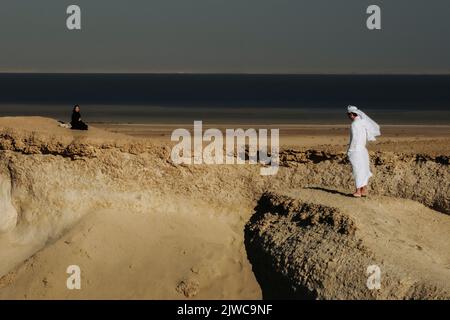 couple regardant l'un l'autre dans les dunes de sable formation de roche à zekreet doha qatar Banque D'Images