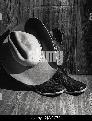 Un gros plan vertical des bottes et un chapeau à l'ancienne tourné en niveaux de gris Banque D'Images