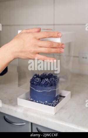 La femme vend, emballant de délicieuses friandises. Boîte transparente pour gâteau Banque D'Images