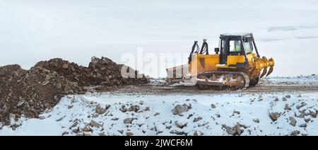 Bulldozer travaillant sur le chantier de construction de routes en phase de nivellement en hiver, espace de copie inclus Banque D'Images