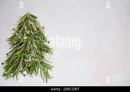 Arbre de Noël créatif de fête, fait de romarin et décoré de grains de poivre et de sel de mer.Style saisonnier.Arrière-plan vert.espace de copie.Élevée Banque D'Images