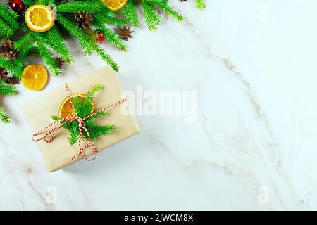 Branches d'un arbre de Noël avec une boîte cadeau zéro déchet, des cônes, des boules de Noël, des tranches d'orange et sur un fond clair.vue du dessus. Un cadre de Noël charmant Banque D'Images