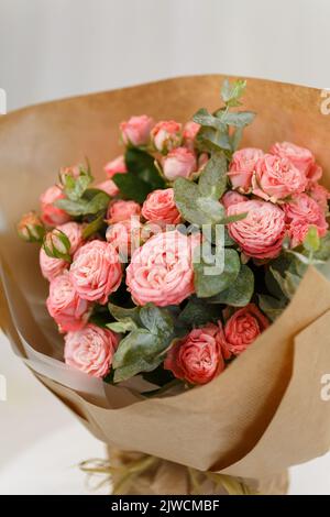 Roses pulvérisées avec des branches d'eucalyptus verts empilées ensemble dans un bouquet festif. Banque D'Images