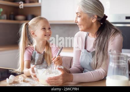 Une bonne grand-mère européenne âgée et une petite petite-fille en tabliers font de la pâte à pâtisserie Banque D'Images