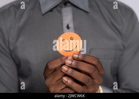 homme noir tenant une découpe en carton souriant visage emoji Banque D'Images