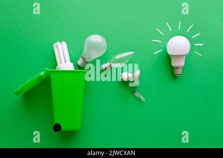 Concept d'économie d'électricité : une nouvelle ampoule LED brillante à économie d'énergie par rapport à plusieurs anciennes ampoules inefficaces sur le chemin d'un bac de recyclage vert. Banque D'Images