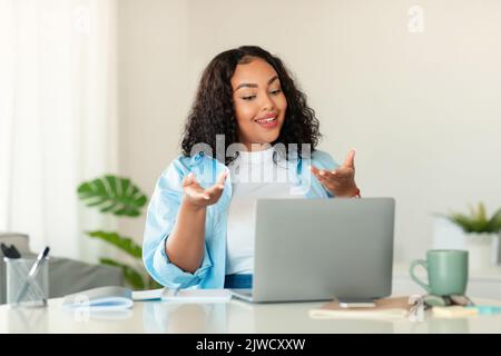 Une femme d'affaires noire fait des appels vidéo en parlant avec un ordinateur portable au bureau Banque D'Images