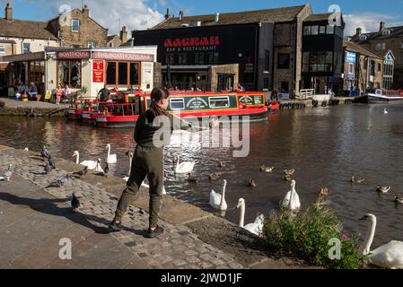 Des filles nourrissant des cygnes à la jonction du canal de Leeds et Liverpool et du canal de la branche de Springs, Skipton, North Yorkshire, Royaume-Uni Banque D'Images