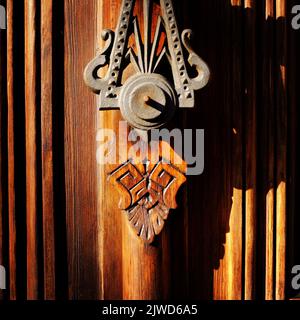 Porte en laiton sur porte en bois avec de fortes ombres projetées par la lumière du soleil de l'après-midi Banque D'Images