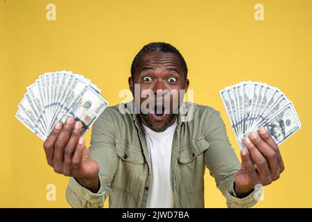 Choqué satisfait adulte africain américain mâle avec la bouche ouverte tenant beaucoup de dollars Banque D'Images
