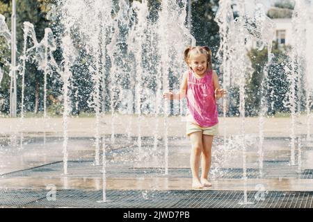 Happy kid jouant dans une fontaine avec de l'eau Banque D'Images