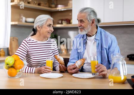 Portrait d'un couple de personnes âgées gaies prenant le petit déjeuner ensemble dans la cuisine intérieure Banque D'Images