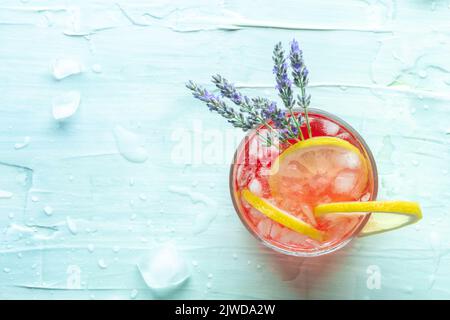 Cocktail d'été frais ou farce au citron et à la lavande, boisson fraîche aux agrumes avec glace, prise d'en haut sur fond bleu avec un endroit pour le texte Banque D'Images