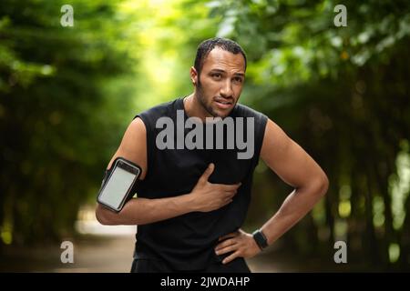 Sportif afro-américain souffrant de douleurs cardiaques, s'entraîner à l'extérieur Banque D'Images