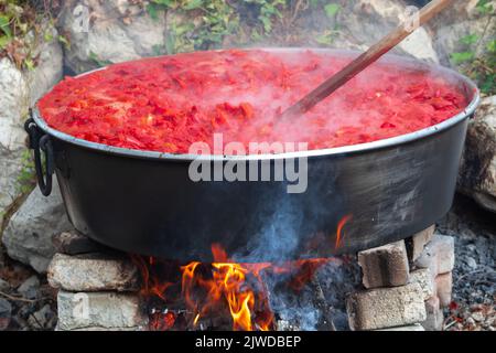 Pâte de tomate traditionnelle sur le feu de bois dans les chaudrons sur la rue, foyer sélectif Banque D'Images