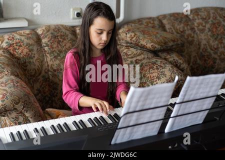 petite fille jouant sur un nouveau synthétiseur dans la vieille chambre Banque D'Images