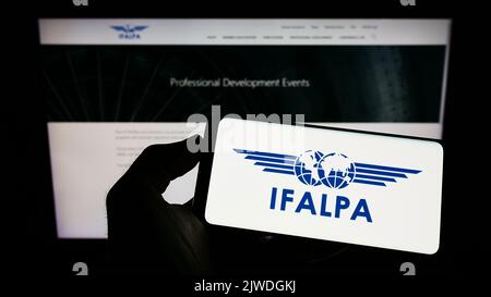 Personne tenant un téléphone portable avec le logo de l'association pilote internationale IFALPA à l'écran en face de la page web. Mise au point sur l'affichage du téléphone. Banque D'Images
