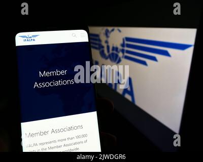 Personne tenant un téléphone portable avec la page web de l'association internationale pilote IFALPA à l'écran devant le logo. Concentrez-vous sur le centre de l'écran du téléphone. Banque D'Images