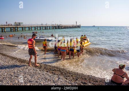 Sotchi, Russie - 22 août 2018 : les touristes en vacances s'assoient sur une banane gonflable pour monter sur les vagues de la mer un jour d'été chaud Banque D'Images