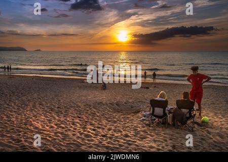 Vacanciers profitant d'un coucher de soleil spectaculaire sur la baie de Fistral à Newquay en Cornouailles au Royaume-Uni en Europe. Banque D'Images