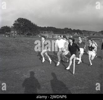 1960s, historique, jeunes adultes membres d'un club d'athlètes amateurs sur une course d'entraînement dans un parc public, avec entraîneur masculin, Écosse, Royaume-Uni. Banque D'Images