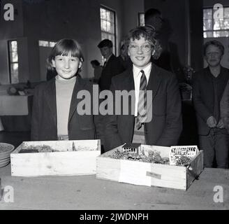 1960s, historique, lauréats... deux écolières debout pour une photo avec leurs jardins miniatures qu'elles ont créés pour un concours scolaire. Banque D'Images