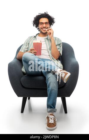 jeune homme souriant avec pop-corn assis sur une chaise Banque D'Images