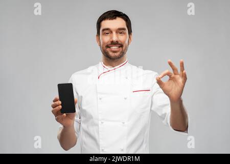 joyeux chef masculin avec un smartphone montrant le signe ok Banque D'Images