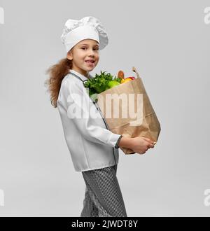 fille dans le toque du chef tenant le sac de papier avec la nourriture Banque D'Images