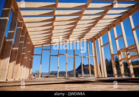 Vue du bas de la maison en bois dans la maison de style scandinave en construction sur fond bleu ciel. Banque D'Images