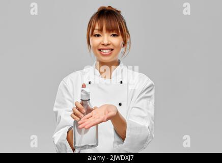 chef féminin appliquant un désinfectant pour les mains ou du savon liquide Banque D'Images
