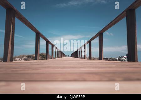 Longue promenade sur la jetée en bois et main courante dans la plage de Quiaios avec une perspective basse et le ciel bleu au-dessus. Lignes d'interligne Banque D'Images