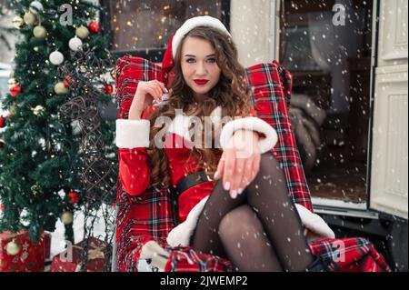 Jeune femme en costume de santa se reposant au camping d'hiver. Concept de célébration du nouvel an Banque D'Images