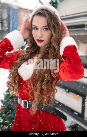 Jeune femme en costume de santa se reposant au camping d'hiver. Concept de célébration du nouvel an Banque D'Images