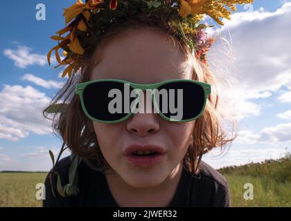 visage fille 5 ans dans des lunettes de soleil noires contre le ciel, temps d'été concept. Banque D'Images