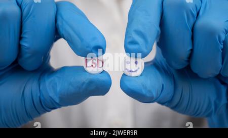 Pilules LSD bleues et rouges dans les mains du médecin, médicament psychédélique pour le traitement des stades sévères de la dépression. Banque D'Images