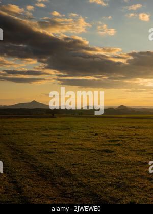 Coucher de soleil romantique sur un champ dans le nord de la Bohême. Le ciel est calme et avec peu de nuages et de soleil au-dessus de l'horizon. Banque D'Images