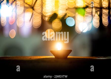 une lampe à huile en faïence solitaire est fixée contre des boules de bokeh colorées montrant l'éclairage et la décoration pendant le festival hindou de diwali montrant un Banque D'Images