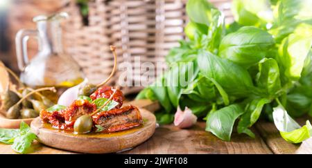 Câpres et tomates séchées avec des herbes dans l'huile d'olive. Grands câpres. Hors-d'œuvre traditionnels en Italie avec ail, herbes de Provence et basilic. Ingrédients pour la bruschetta et l'apéritif. Photo de haute qualité Banque D'Images