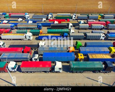 Vue aérienne des camions colorés dans le terminal au coucher du soleil en été. Vue de dessus du centre logistique. Industrie lourde. Transport. Transport de marchandises, expédition Banque D'Images