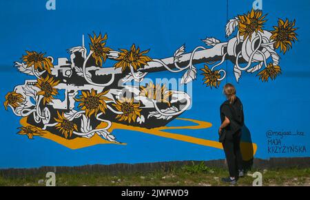 GDANSK, POLOGNE. 05 septembre 2022. Une jeune femme regarde une fresque pro-ukrainienne créée par l'artiste polonaise Maja Krzyzynska. Près de 30 peintures murales anti-guerre ont été peintes sur le mur à l'arrêt PKM Gdansk Jasien Mapka dans le cadre du projet "en solidarité avec l'Ukraine" lancé par le PKM et l'Académie des beaux-arts de Gdansk. Beaucoup de ces peintures murales sont liées au conflit russo-ukrainien de 2022. Crédit : ASWphoto/Alamy Live News Banque D'Images